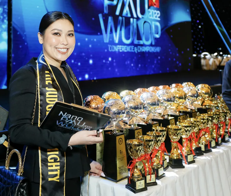 Tina as a judge at a cosmetic tattoo competition, beside the trophies